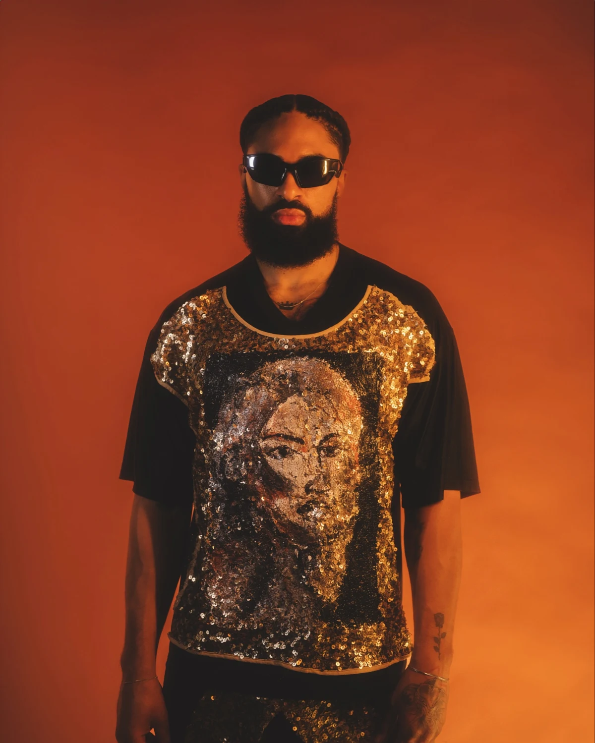 LaShawn wearing a gold sequined BEILHARZ shirt against a warm orange backdrop